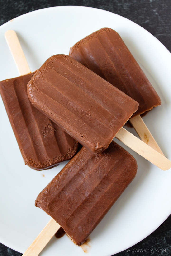 Overhead view of homemade vegan chocolate fudgesicles on a white plate