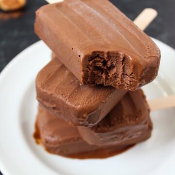 Homemade chocolate vegan fudgesicles stacked on a white serving plate