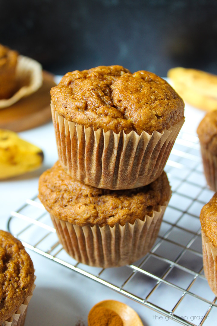 Two gluten-free vegan banana muffins stacked on a cooling rack after baking