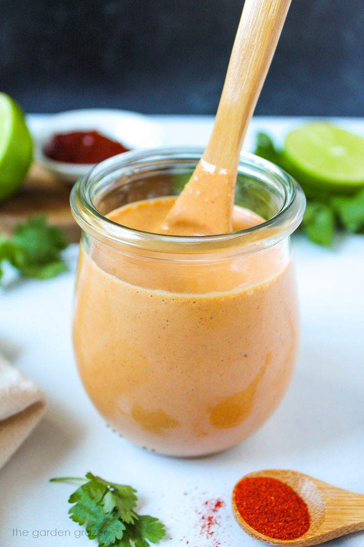 Vegan creamy chipotle lime dressing in a small serving jar with wooden spoon