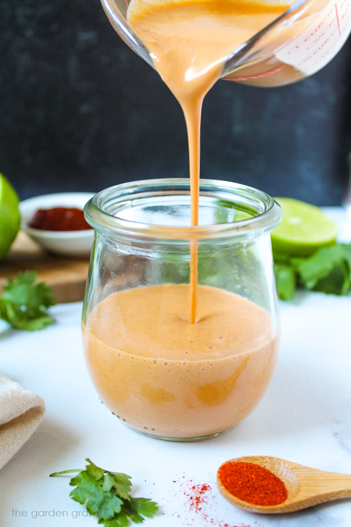 Blended creamy chipotle lime dressing being poured into a serving glass