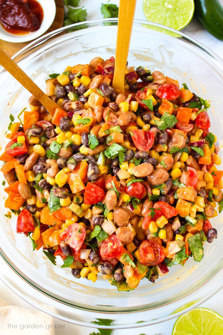 Overhead view of Mexican bean salad tossed with creamy chipotle lime dressing in a large glass bowl